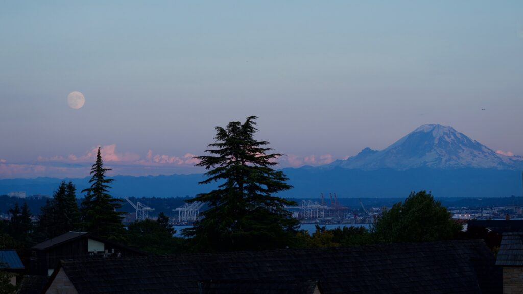 Mount Rainier and the Seattle waterfront at dusk with a rising moon